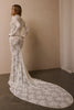 A woman modeling a long-sleeve white lace mermaid gown with a high neck and a dramatic train, standing in a minimalist studio with beige walls and a concrete floor_XS_