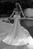 Black and white photo of a bride in a wedding dress and bow by a pool.