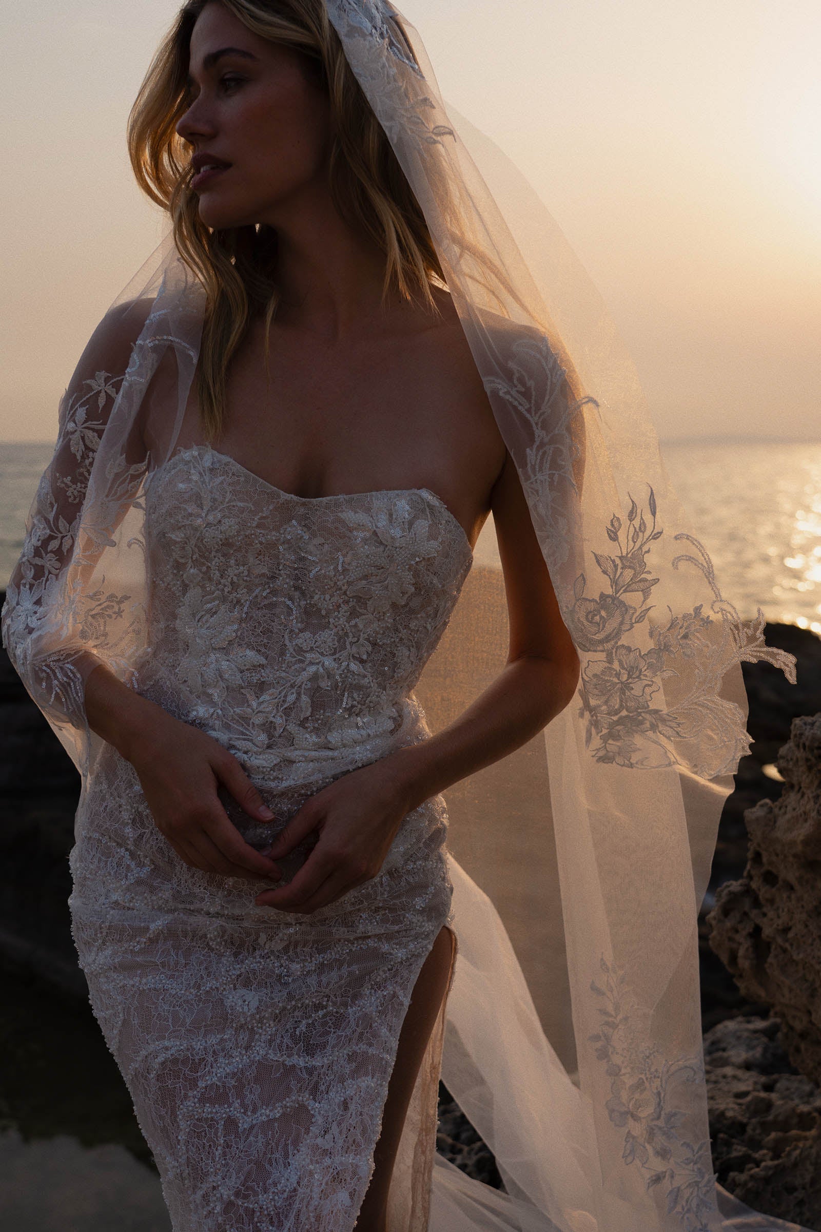 Woman in a strapless lace wedding dress with a veil at sunset_XS_