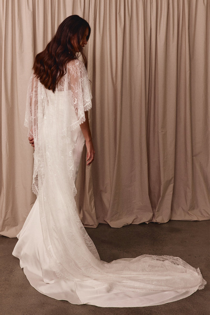 Woman wearing a white wedding dress with a chantilly lace cape