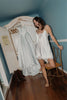 Woman in a satin slip dress next to her wedding gown.