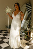 Woman in a V-neck lace wedding dress holding a bouquet