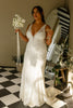 Woman in a V-neck lace wedding dress holding a bouquet