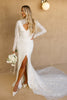 Woman in a V-neck lace wedding dress with bridal sleeves against a beige wall.