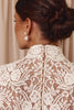 Close-up of a person wearing a white lace gown with pearl buttons and earrings.