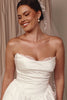 Woman wearing a white strapless wedding dress with a veil and pearl earrings