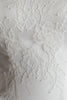 Close-up of a white lace fabric with floral embroidery and textured mesh backing.