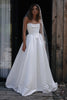 Woman wearing a white wedding dress with a veil standing against a rustic wooden wall.