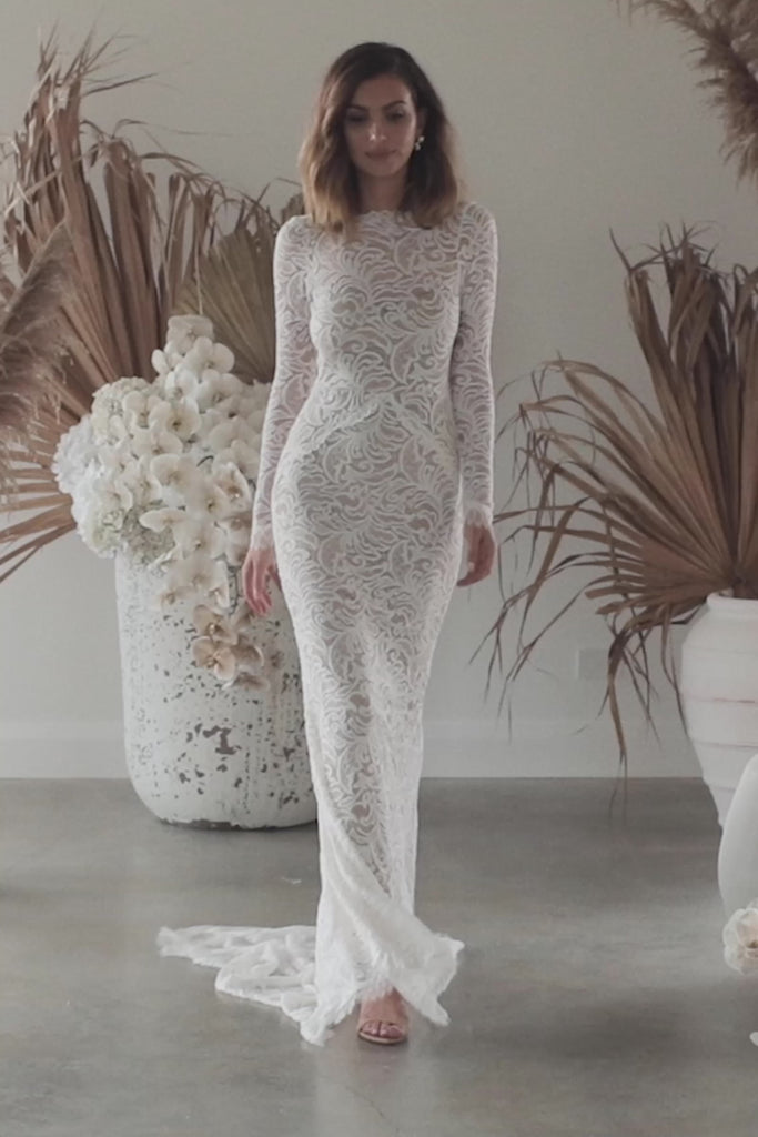 A woman walking in a high neck lace wedding dress.