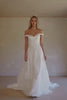 Video of a woman wearing an off-the-shoulder white wedding dress with a fitted bodice and flowing skirt